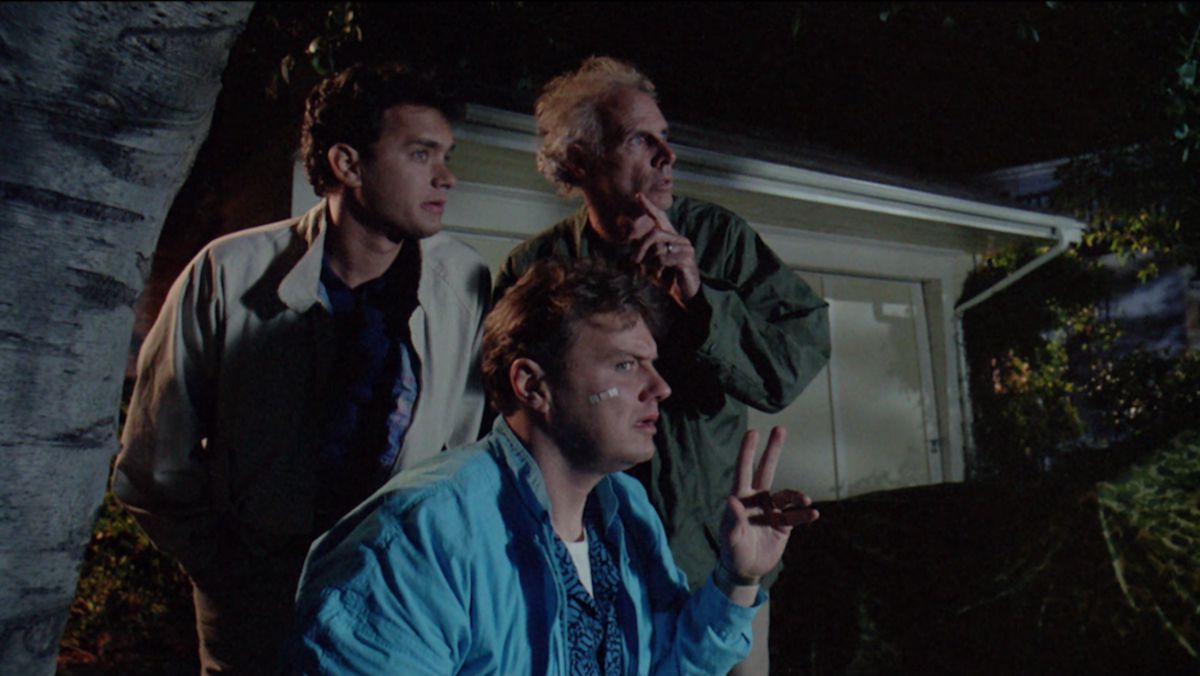 Three men (LR Tom Hanks, Rick Ducommun, Bruce Dern) hide behind a garbage can at night and stare at something off-screen.