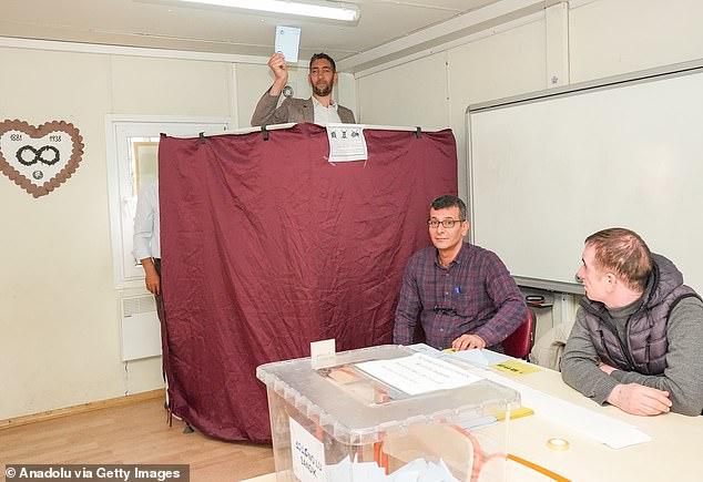 Sultan Kosen, who towers at 2.5 meters above everyone else in the world, was seen today peering out of the polling station's privacy curtain