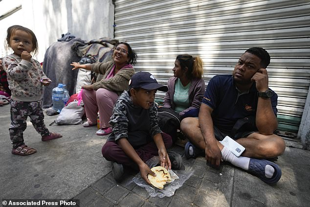 A migrant family from Venezuela eats breakfast along the railroad tracks in Mexico City, Tuesday, March 26, 2024. (AP Photo/Fernando Llano)