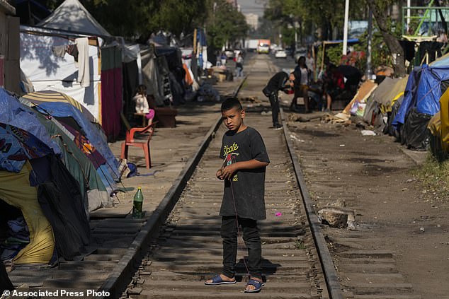 A young migrant from Venezuela plays with a spinning top on the railway tracks lined with tents and makeshift shelters in Mexico City, Tuesday, March 26, 2024. (AP Photo/Fernando Llano)