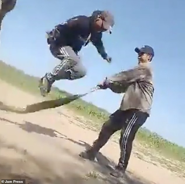 Two of the unidentified men were seen holding the enormous boa constrictor by the neck and tail, while a third man stood between them on a dirt road in rural Argentina.