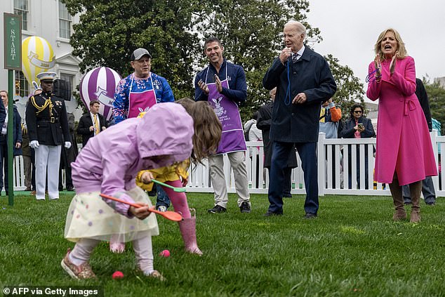 President Joe Biden blows the starting whistle as Jill Biden cheers on the children during the Egg Race