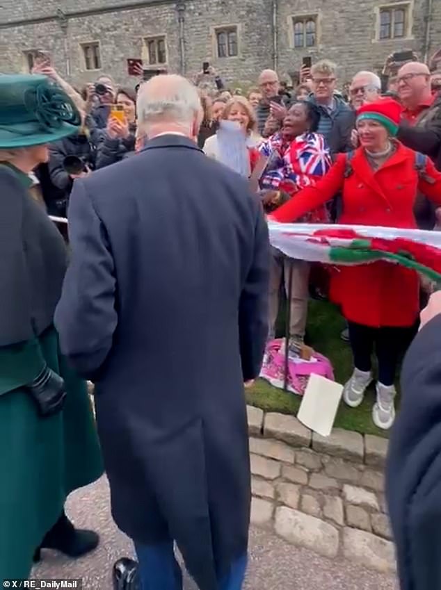 A woman, holding a Welsh flag and wearing a matching bright red coat and hat, called King to get his attention