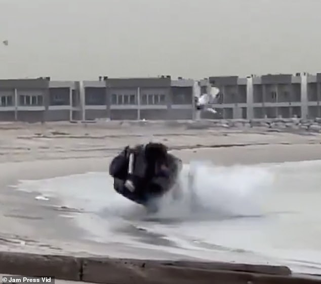 The car falls through the water and the driver seems to fly out the window