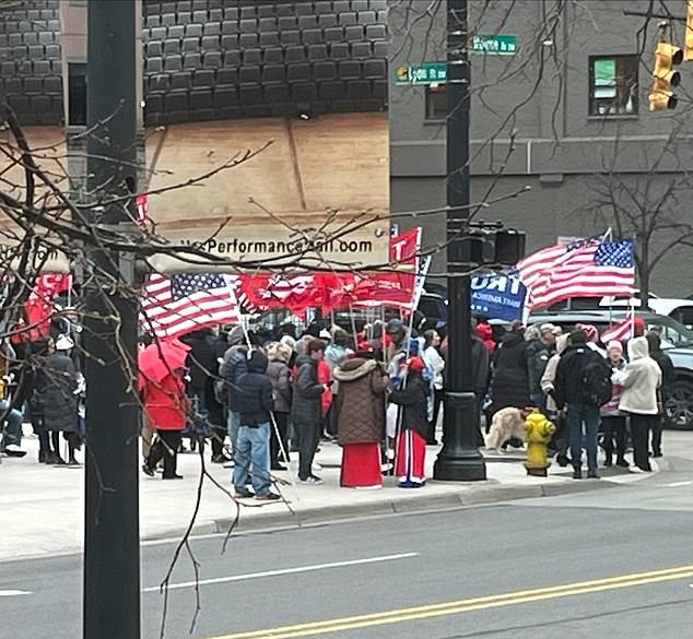 Trump supporters wave flags and signs as they await Trump's arrival in Grand Rapids, MI