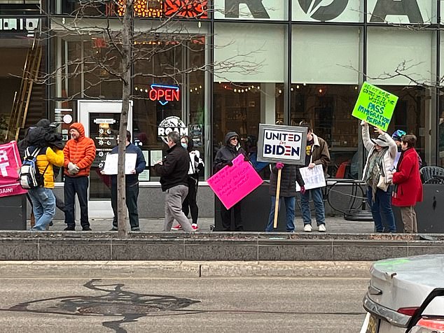 Anti-Trump protesters across from DeVos Place await Trump's arrival.  Some carried signs promoting the bipartisan immigration deal that Trump helped stop in Congress.  Others showed their support for President Biden