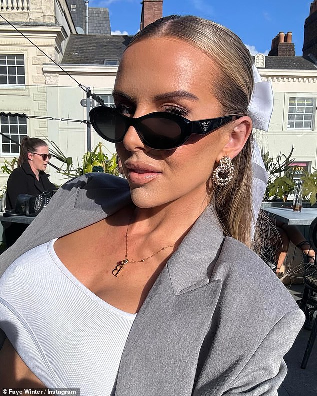 Faye soaked up the sun at her table wearing dark sunglasses and styled her long blonde locks in a neat half-updo, complete with a white satin bow