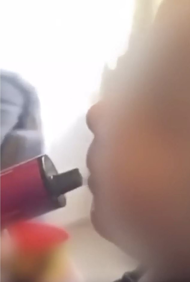 In a series of disturbing video clips released online, the baby - believed to be aged between one and two - is seen inhaling a pink vapor (pictured)