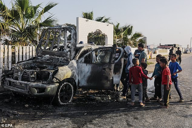 People stand near a wrecked car belonging to the NGO World Central Kitchen (WCK)