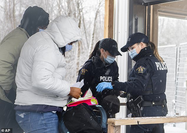 Canadian officers check the identification details of two people who entered Canada via Roxham Road at the Canada-US border