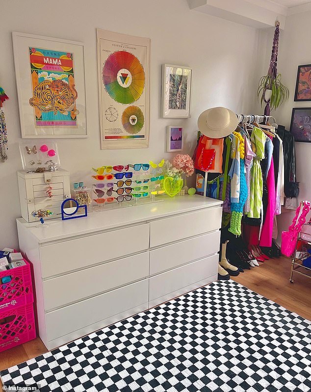 Her beauty salon is bursting with color in every corner with a clothes rack, glasses stand, checked rug, bright pink crates and wall posters