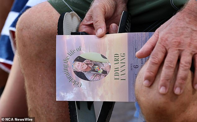 The photo shows a man holding a memorial that was handed out during Saturday's service