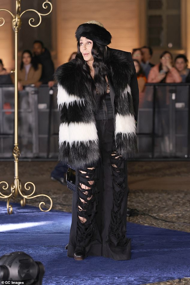 Cher, 77, stood out in a statement fur coat and distressed trousers