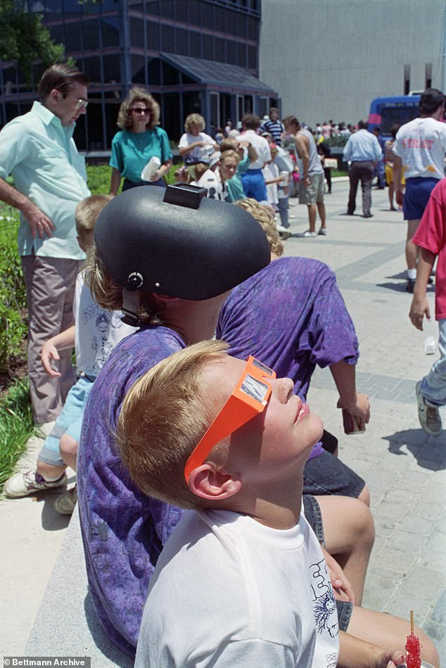 At the Houston Museum of Natural Science, children look up at the July 1991 eclipse in Houston.  One of them wears a welding helmet to shield his eyes from the sun