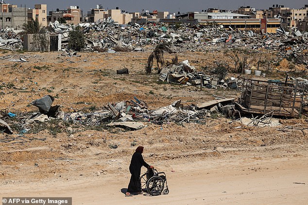 Palestinian elderly woman pushes a wheelchair past rubble in Khan Yunis on April 7, 2024 after Israel withdrew troops from the southern Gaza Strip, six months into the devastating war following the October 7 attacks