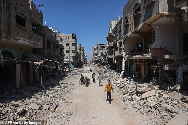 Palestinians use a road full of damaged and destroyed buildings in Khan Yunis on April 7, 2024