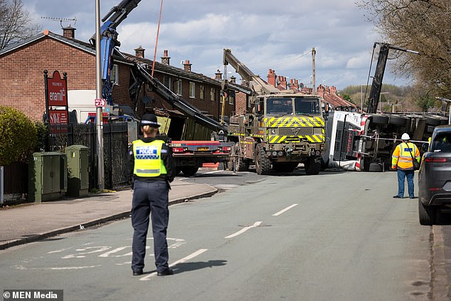 A police officer watches as emergency services attempt to remove the crane embedded in the building