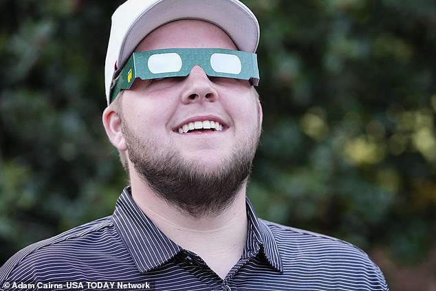 Tanner Causey, of Millbrook, Alabama, looks through eclipse glasses during a practice round for the Masters Tournament golf tournament at Augusta National Golf Club