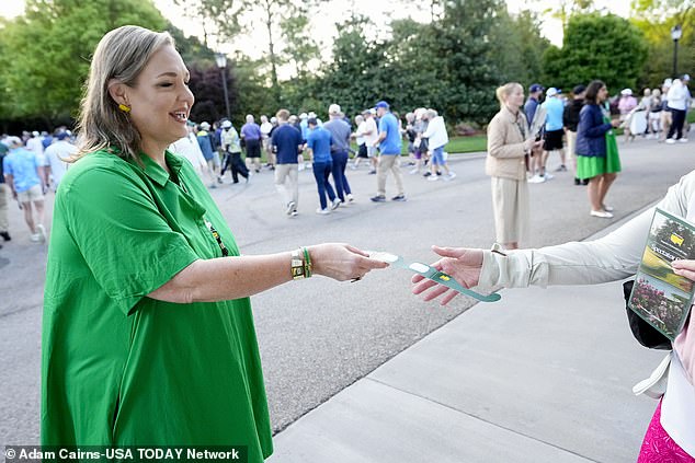 Karen Pemberton hands out eclipse glasses to customers at the gate during a practice round