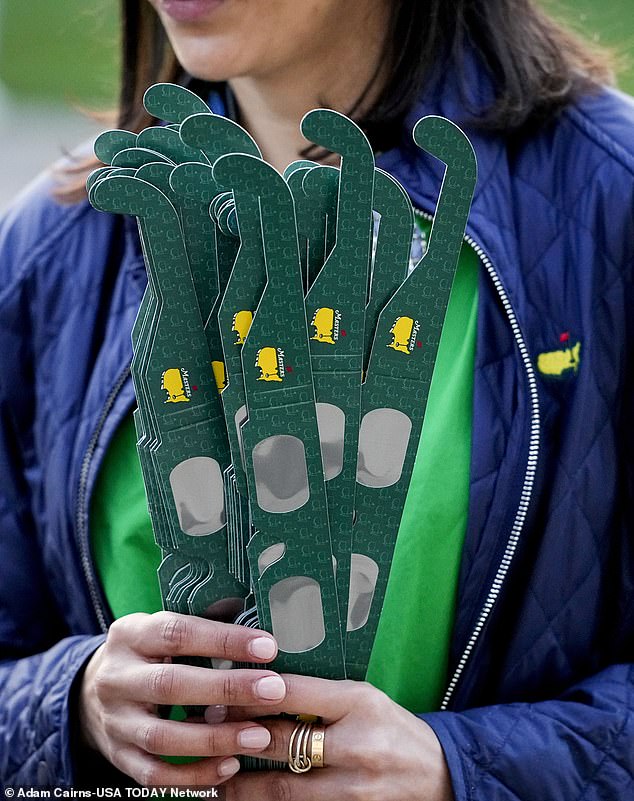 Nadine Bassalio, from Augusta, Georgia, hands out eclipse glasses during a practice round for the Masters Tournament golf tournament at Augusta National Golf Club