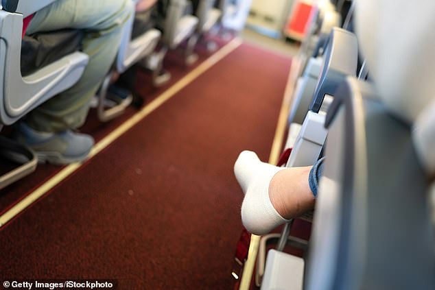 An airplane passenger sits with his shoes off