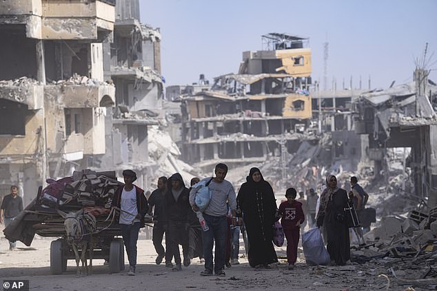 Palestinians walk through the destruction in the aftermath of an Israeli air and ground offensive in Khan Younis