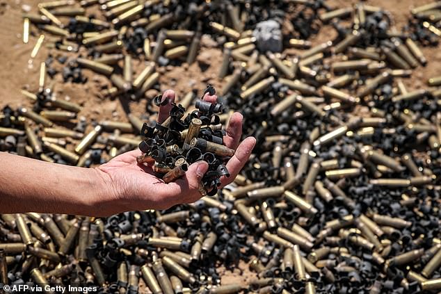 A person holds a handful of spent bullet casings over a larger pile in Khan Younis on April 7, 2024