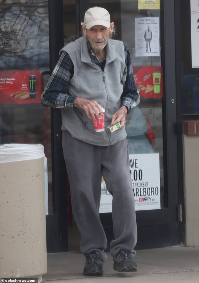 He was dressed perfectly for a casual day out, wearing a gray fleece sweater over a casual dark blue checked shirt, gray sweatpants and black sneakers.