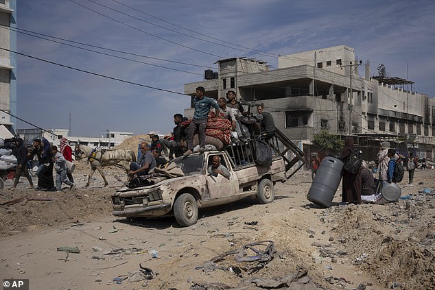 Palestinians drive and walk through the destruction in the aftermath of an Israeli air and ground offensive in Khan Younis