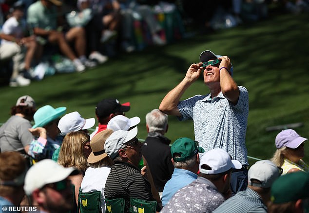 Videos shared on social media showed people looking at the graying sky to catch a glimpse of the phenomenon that left only the sun's outer atmosphere visible, briefly turning the outdoors dark during the day.  In the photo, people use goggles to observe the solar eclipse during the Masters in Augusta, Georgia