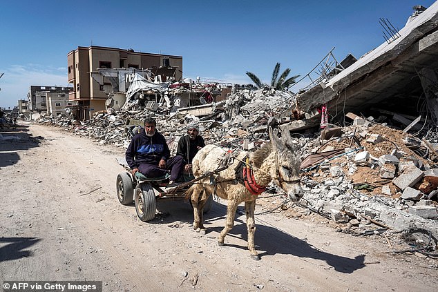 Two men sit in a donkey-drawn cart as it passes the rubble of a destroyed building in Khan Yunis on April 7, 2024, after Israel withdrew its ground forces from the southern Gaza Strip, six months into the devastating war sparked by the attacks. October 7.