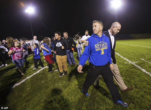 Bremerton High assistant football coach Joe Kennedy, front, walks off the field with his lawyer, right, October 16, 2015, after praying at the 50-yard line following a football game in Bremerton, Washington