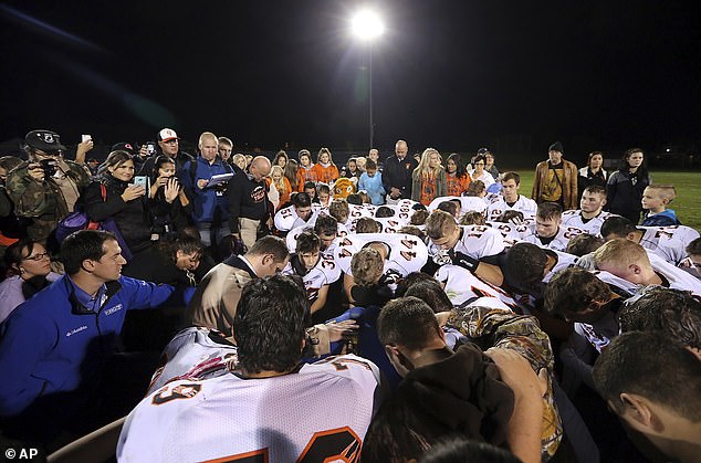 Joe Kennedy is surrounded by Centralia High School football players as they kneel and pray with him on the field after their 2015 game