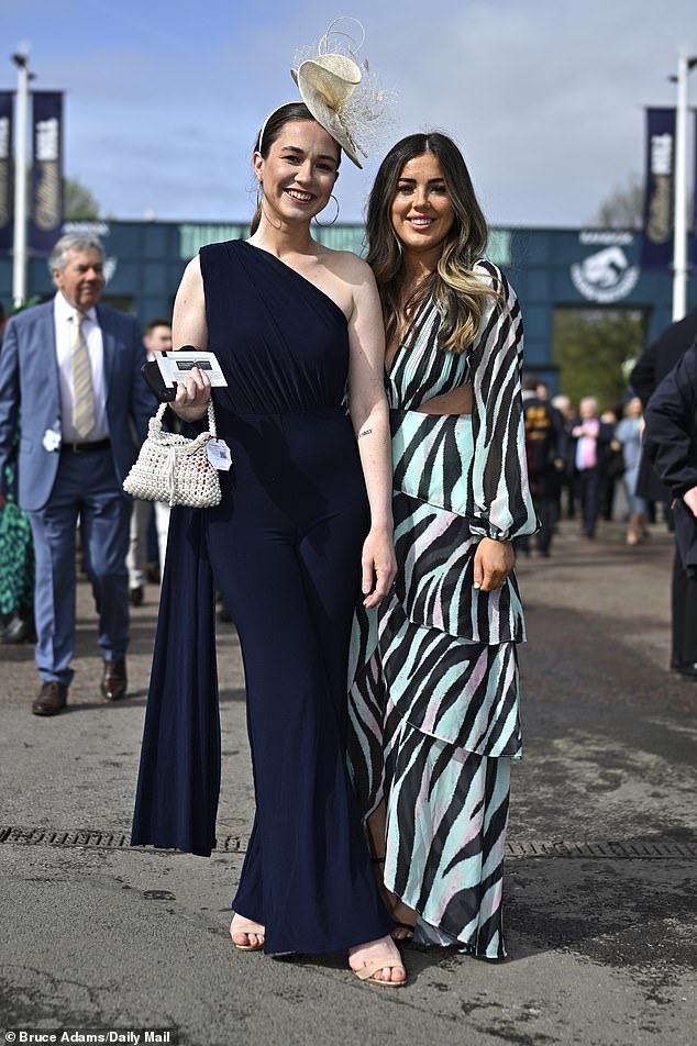 Cold shoulder!  Friends put on a glamorous show, with one wearing an elegant one-shoulder jumpsuit and the other opting for a fun dress with zebra print and cutouts