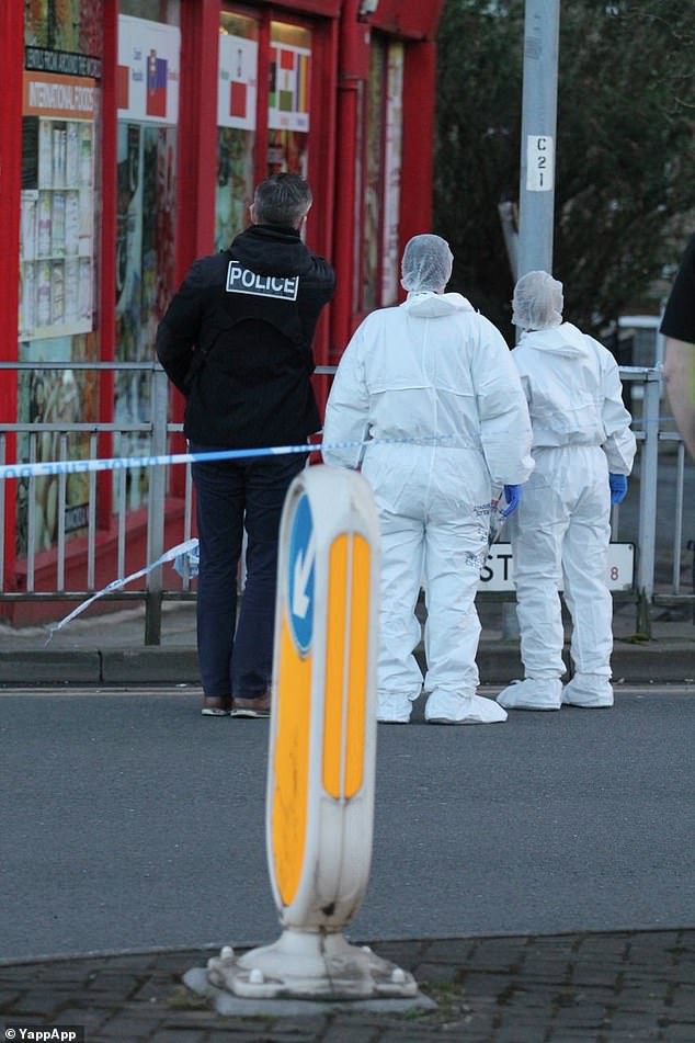 Police officers in white forensic gear stand inside a cordon at the scene of the stabbing in Bradford