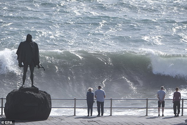 The deceased person, a 53-year-old Czech tourist, fell into rough seas near the northern resort of Puerto de la Cruz and drowned despite efforts to save him.  Pictured: People watch high waves at Candelaria, Tenerife on Wednesday