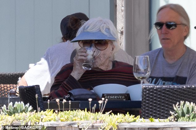 Shirley kept herself out of the sun with a lavender visor to complement her trousers