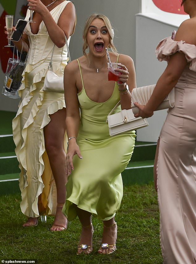 A group of friends are seen having fun in Aintree today, as a woman smiles at the camera with a drink in her hand