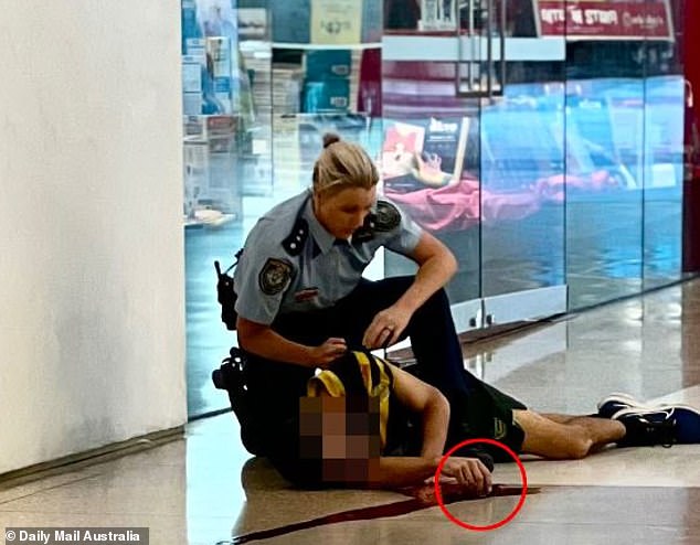 The police officer (pictured holding the knifeman) has been hailed as a hero by Prime Minister Anthony Albanese