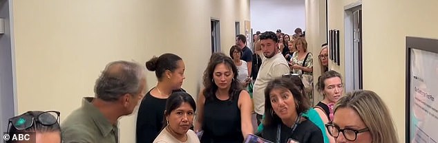 Shoppers huddled in the staff room hallway, looking at their phones in confusion and concern