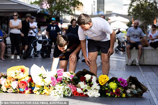 Children are seen laying flowers in tribute to the victims and the people fighting for their lives in the hospital