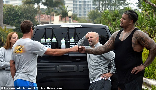 A member of the USC Trojans is seen bumping fists with Aaron Rodgers after their practice