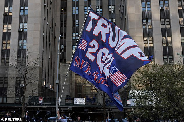 A Trump supporter holds a flag in support of the former president's re-election outside the Manhattan Criminal Courthouse on Monday before his arrival