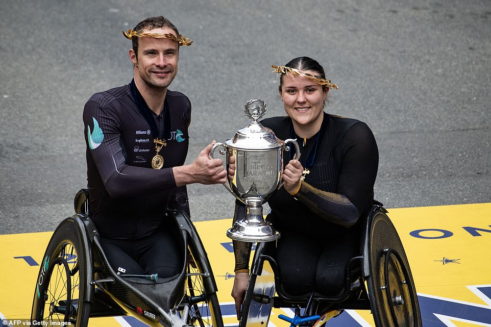 Swiss athlete Marcel Hug and English athlete Eden Rainbow Cooper hold a trophy after finishing in first place in the men's and women's professional wheelchair field