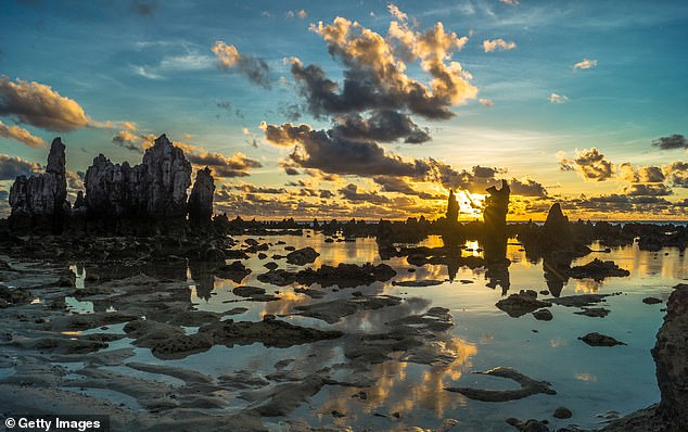 The sun rises between the rocky outcrops on Anabare Beach, Nauru Island, South Pacific