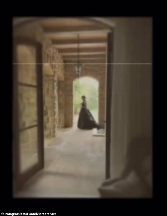 The video continues with an image of a woman in a long dress, lit down a hallway