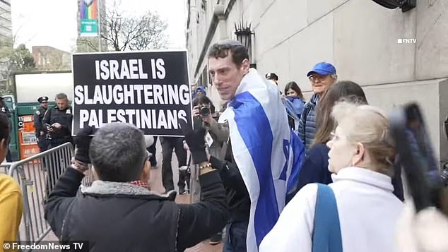 A pro-Israeli protester is seen with an Israeli flag on his back and a yamaka on his head as he stares at pro-Palestinian demonstrators