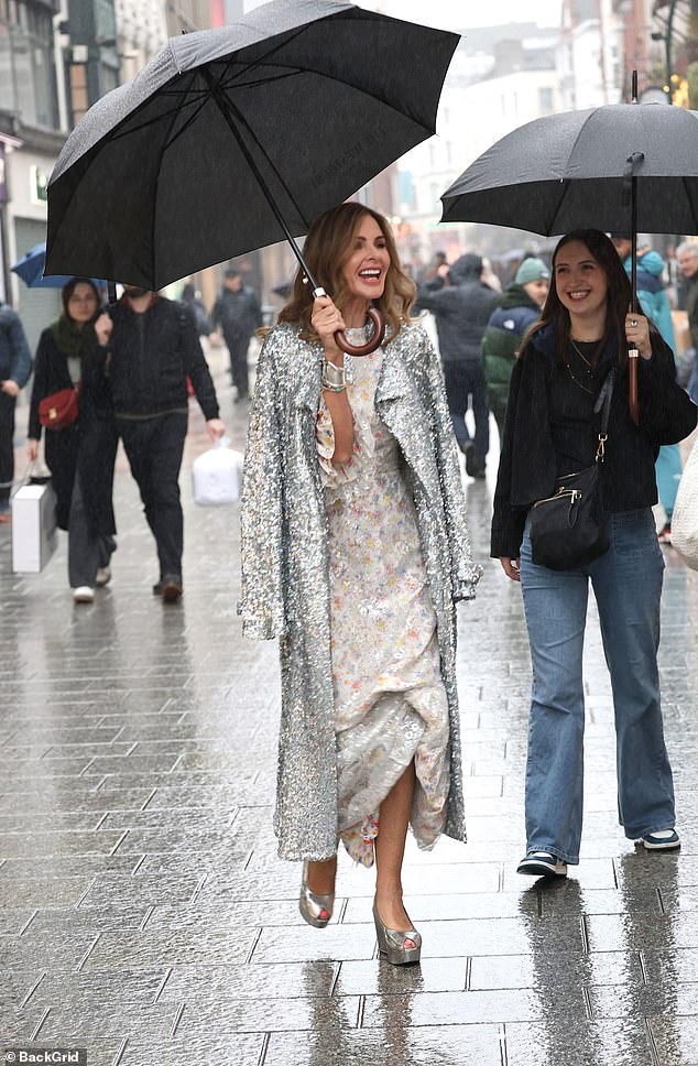 Arriving at the department store earlier in the day in the rain, she completed the look with a long silver sequin coat