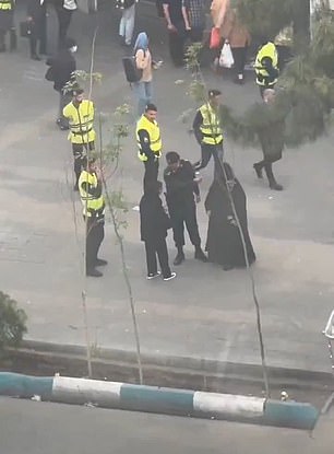 A suspected vice police officer is seen speaking stern words to a woman on the street before leading her over a van - despite the fact she appears to be wearing a hijab