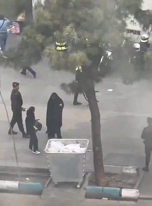 A suspected vice police officer is seen speaking stern words to a woman on the street before leading her over a van - despite the fact she appears to be wearing a hijab